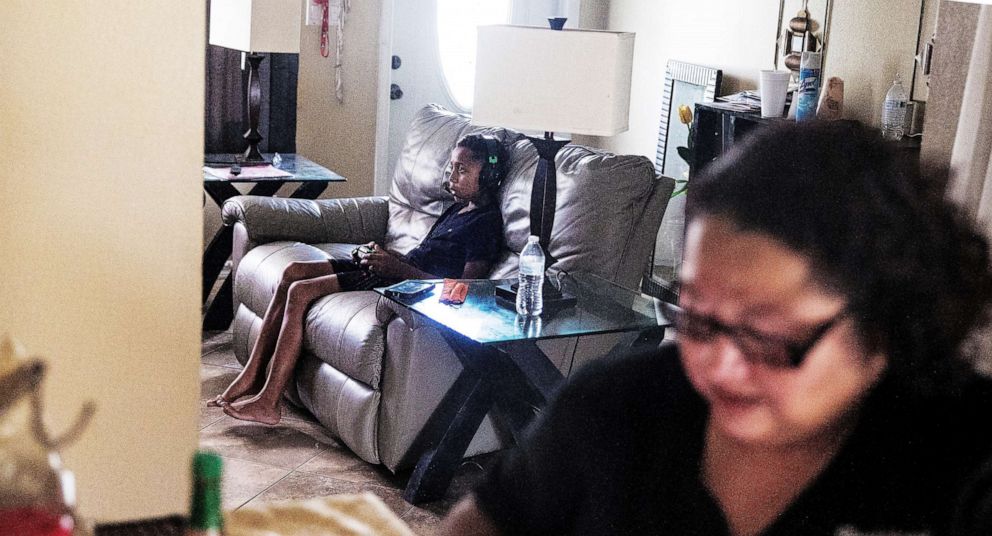 PHOTO: Jayvion Hamilton, 9, plays video games with his sibling, who is in another room  while his mother, Etzia checks her phone in Fort Myers, Fla., July 16, 2020. 