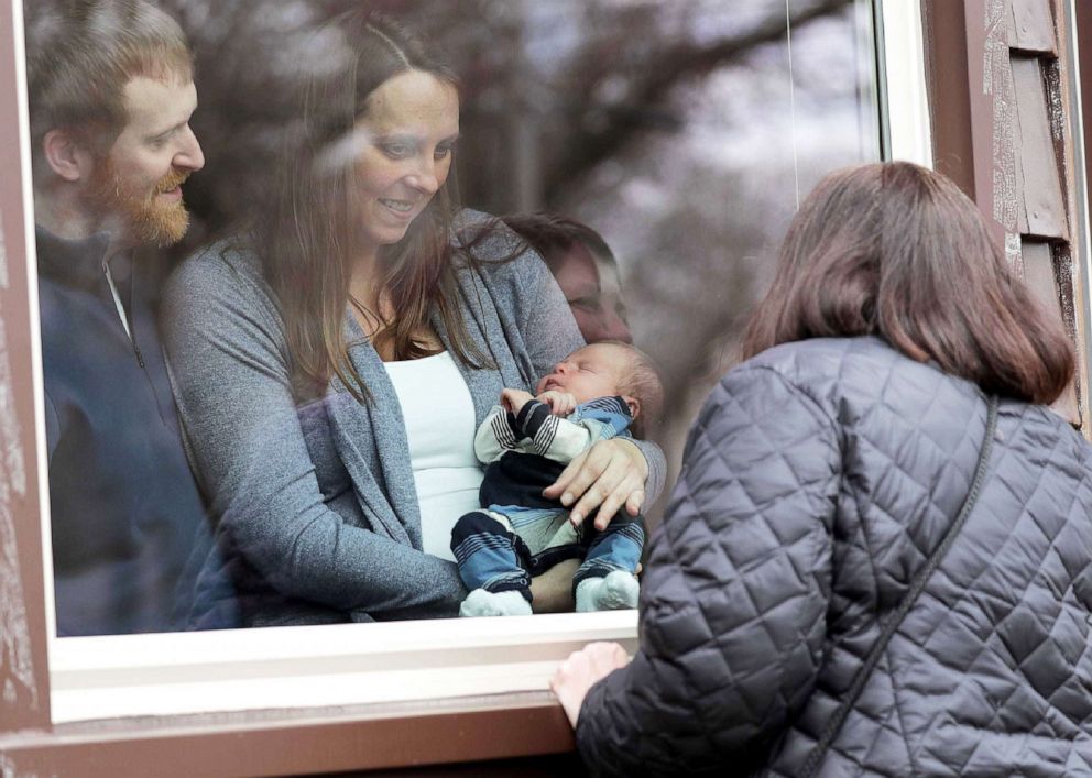 PHOTO: Ryan and Cortney Dvorachek, along with their newborn son Emmett, visit with the baby's grandmother, Sheree Joosten, through the front window of their home in Appleton, Wisc., Dec. 16, 2020.