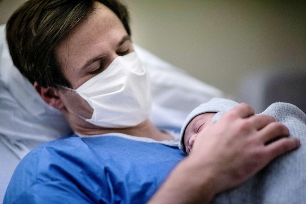 PHOTO: A father wearing a protective mask holds his newborn son against his chest at a maternity ward of a hospital in Paris, Nov. 17, 2020.