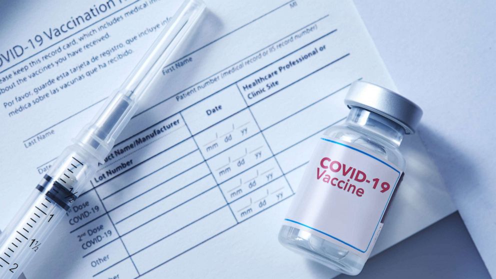 Stock photo: Coronavirus vaccine vial on a vaccination record card with a syringe on the side