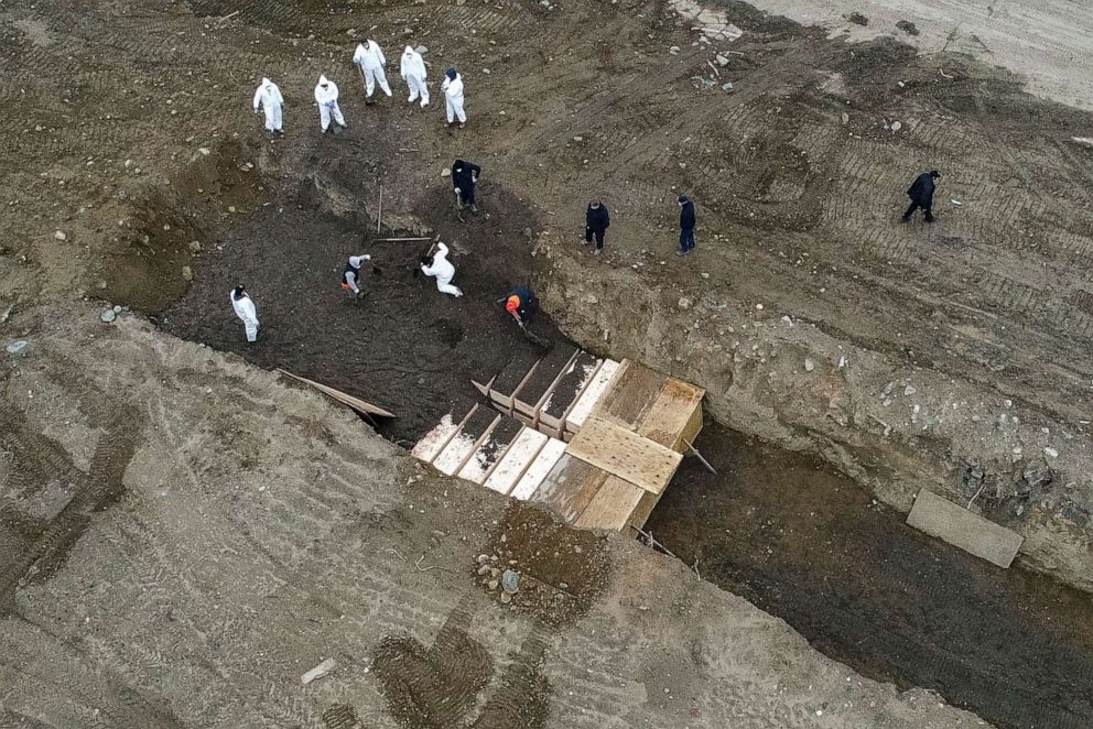 PHOTO: Workers wearing personal protective equipment bury bodies in a trench on Hart Island, April 9, 2020, in Bronx, N.Y. 