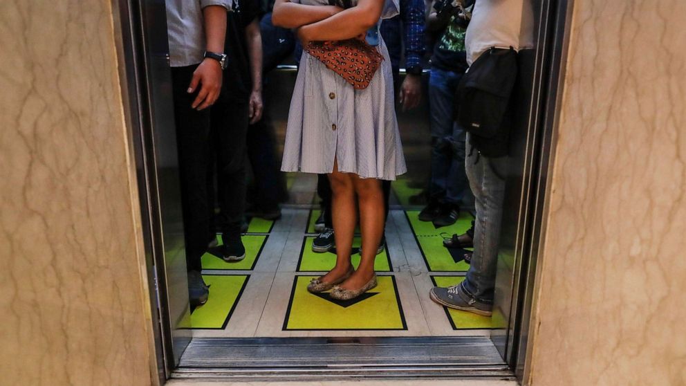 PHOTO: Workers stand on social distancing marks inside an elevator of the Senayan City shopping mall in Jakarta, Indonesia, June 9, 2020.