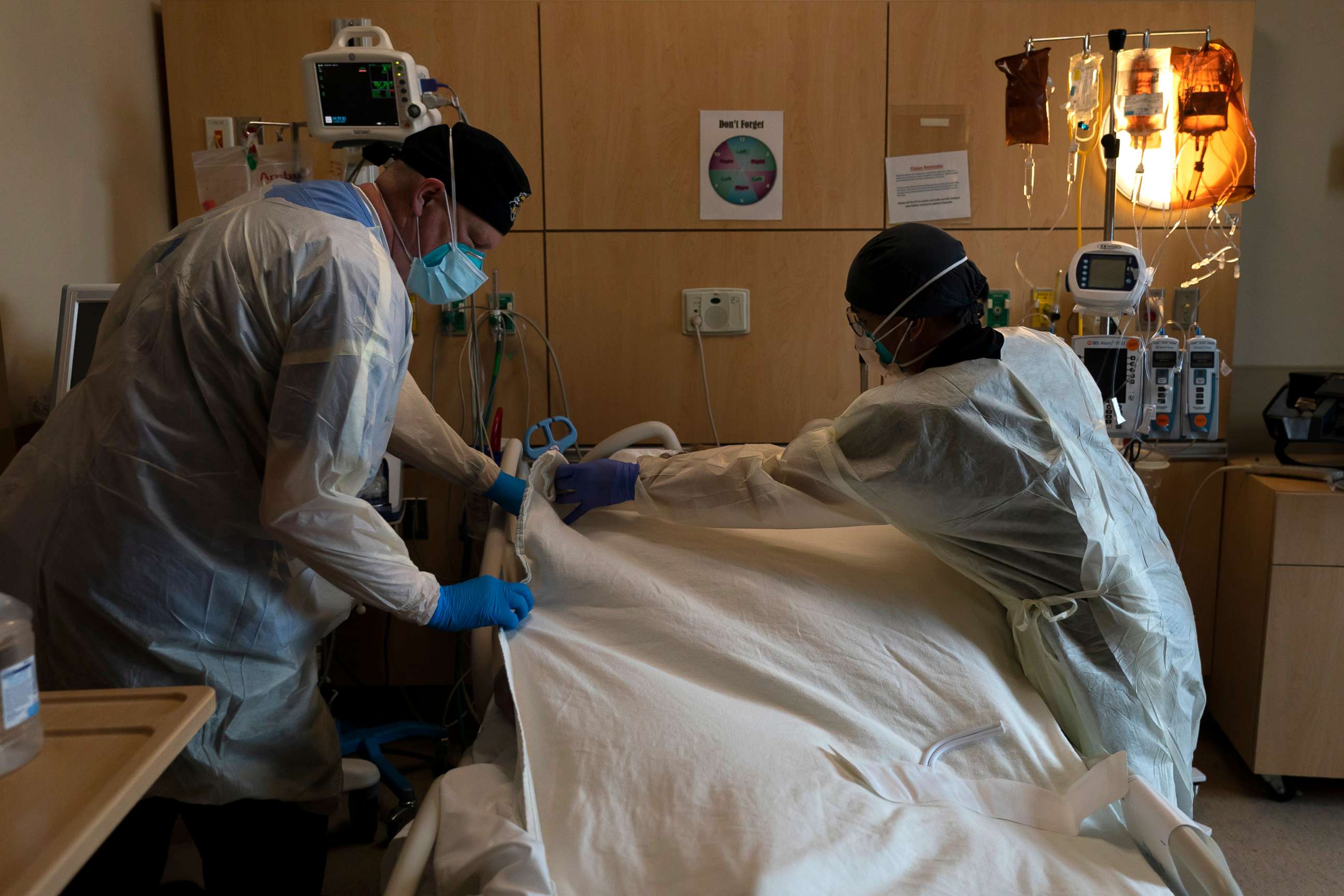 PHOTO: Hospital workers cover a body of a COVID-19 patient with a sheet at Providence Holy Cross Medical Center in Los Angeles, Dec. 14, 2021.