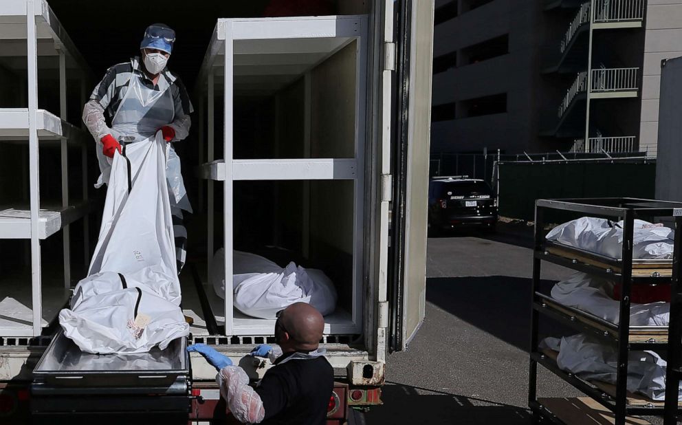 PHOTO: A low-level inmate from El Paso County detention facility works loading bodies wrapped in plastic into a refrigerated temporary morgue trailer in a parking lot of the Medical Examiner's office in El Paso, Texas, Nov. 17, 2020.