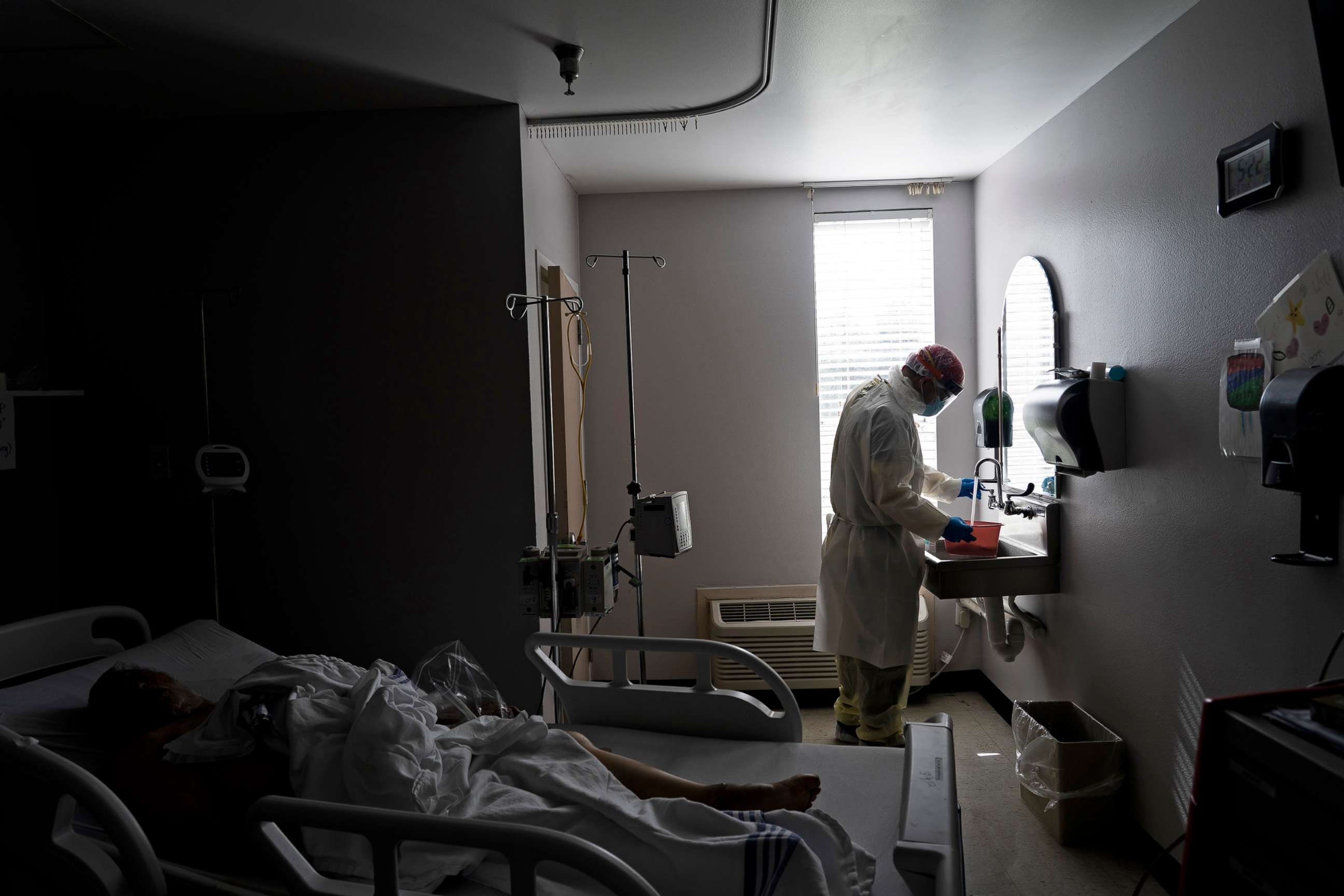 PHOTO: A member of the medical staff wearing full PPE prepares a disinfectant solution to wipe a deceased patient in the Covid-19 intensive care unit in Houston, June 30, 2020.