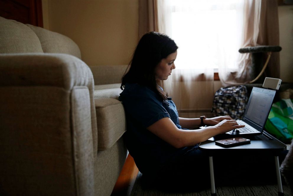 PHOTO: Kate Porter, who still suffers from fevers, shortness of breath, exercise intolerance, and terrible fatigue works as a result of COVID-19, works on her laptop in her living room in Beverly, Mass., Aug. 6, 2020. 