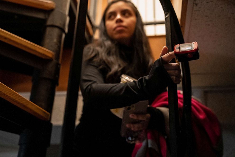 PHOTO: Tiffany Patino, who has struggled with long-haul covid symptoms for a year, wears a pulse oximeter to monitor her vitals as she walks up the stairs at her boyfriends grandmothers home where she lives in Rockville, Md., Dec. 2, 2021.