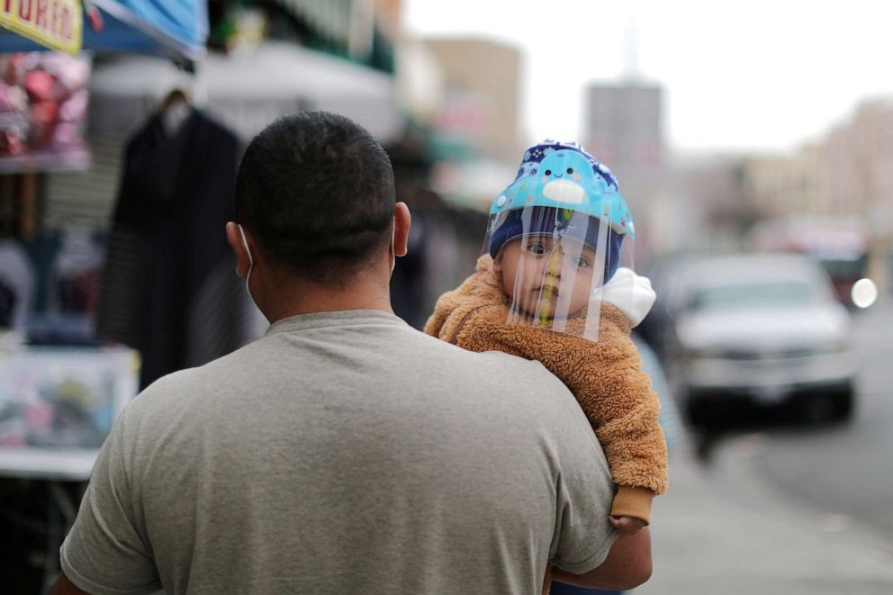 PHOTO: A child wears a coronavirus protective mask while being carried in Los Angeles, Feb. 10. 2021.  