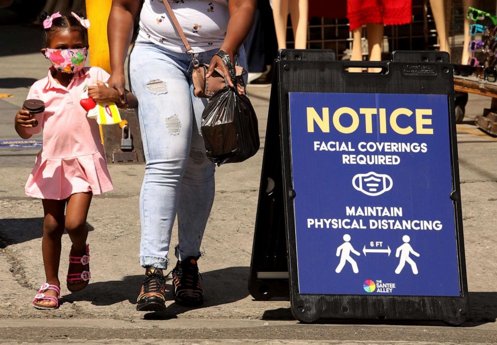 PHOTO: A young shopper,  wearing a mask to protect herself from coronavirus, shops with her mother on Santee Alley in the Garment District, June 30, 2020, in Los Angeles. 