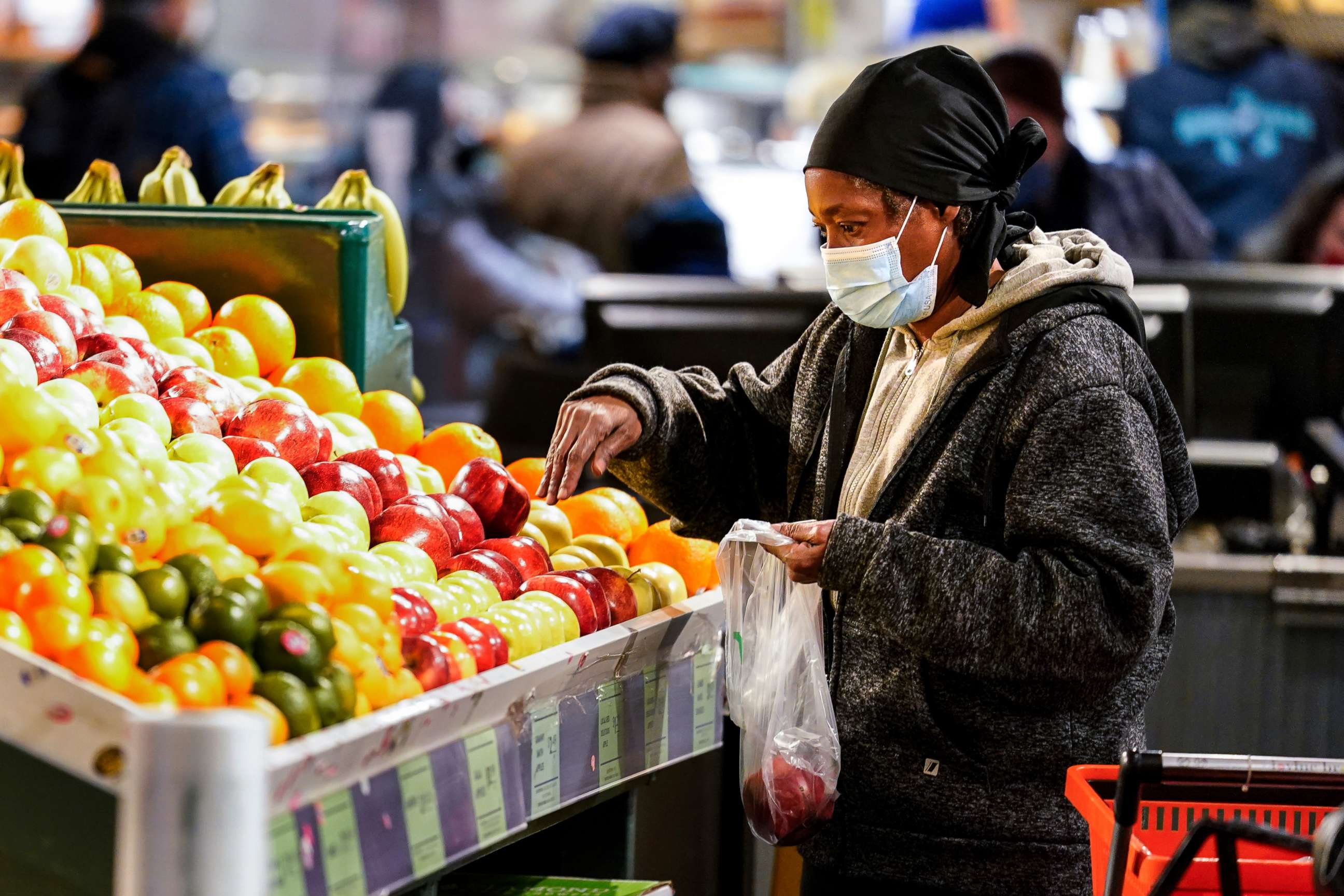 PHOTO: A shopper waring a protective mask as a precaution against the spread of the coronavirus selects fruit at the Reading Terminal Market in Philadelphia, Feb. 16, 2022.