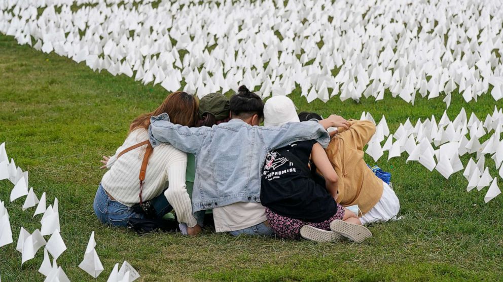 PHOTO: In this Sept. 21, 2021, file photo, visitors sit among white flags that are part of artist Suzanne Brennan Firstenberg's "In America: Remember," a temporary art installation to commemorate Americans who have died of COVID-19, in Washington, D.C.
