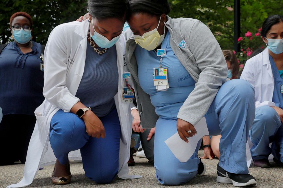PHOTO: Nurses Sasha Dubois and Farah Fevrin kneel during a vigil for George Floyd at Brigham and Women's Hospital in Boston, June 5, 2020.