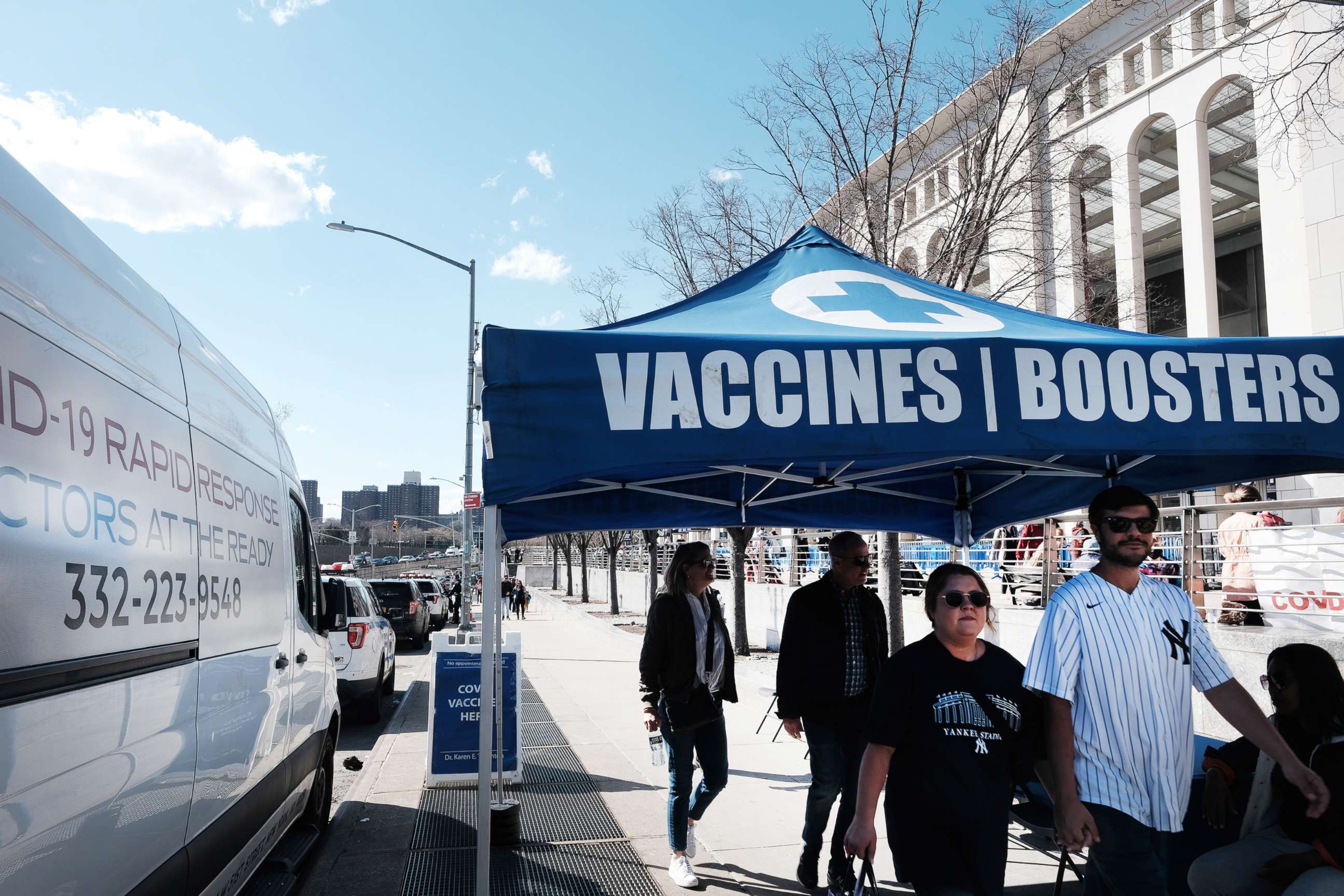 PHOTO: People walk past a A COVID-19 vaccine and testing site outside Yankee Stadium on the Opening Day of the season, April 08, 2022, in New York City.