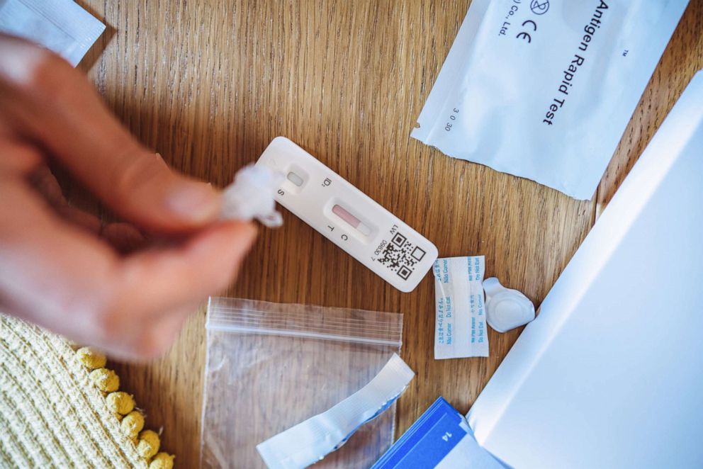 PHOTO: In this undated file photo, a woman squeezes liquid onto a test strip while carrying out a COVID-19 rapid self test at home.