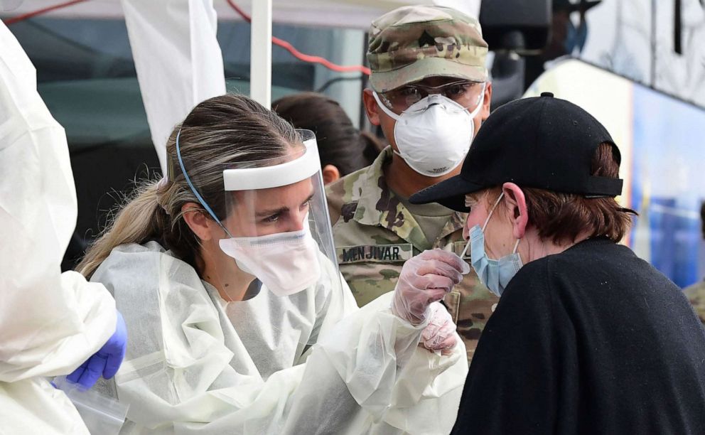 PHOTO: In this Jan. 12, 2022, file photo, a woman receives help with a nasal swab at a BusTest Express Covid-19 mobile testing site in Paramount, Calif.