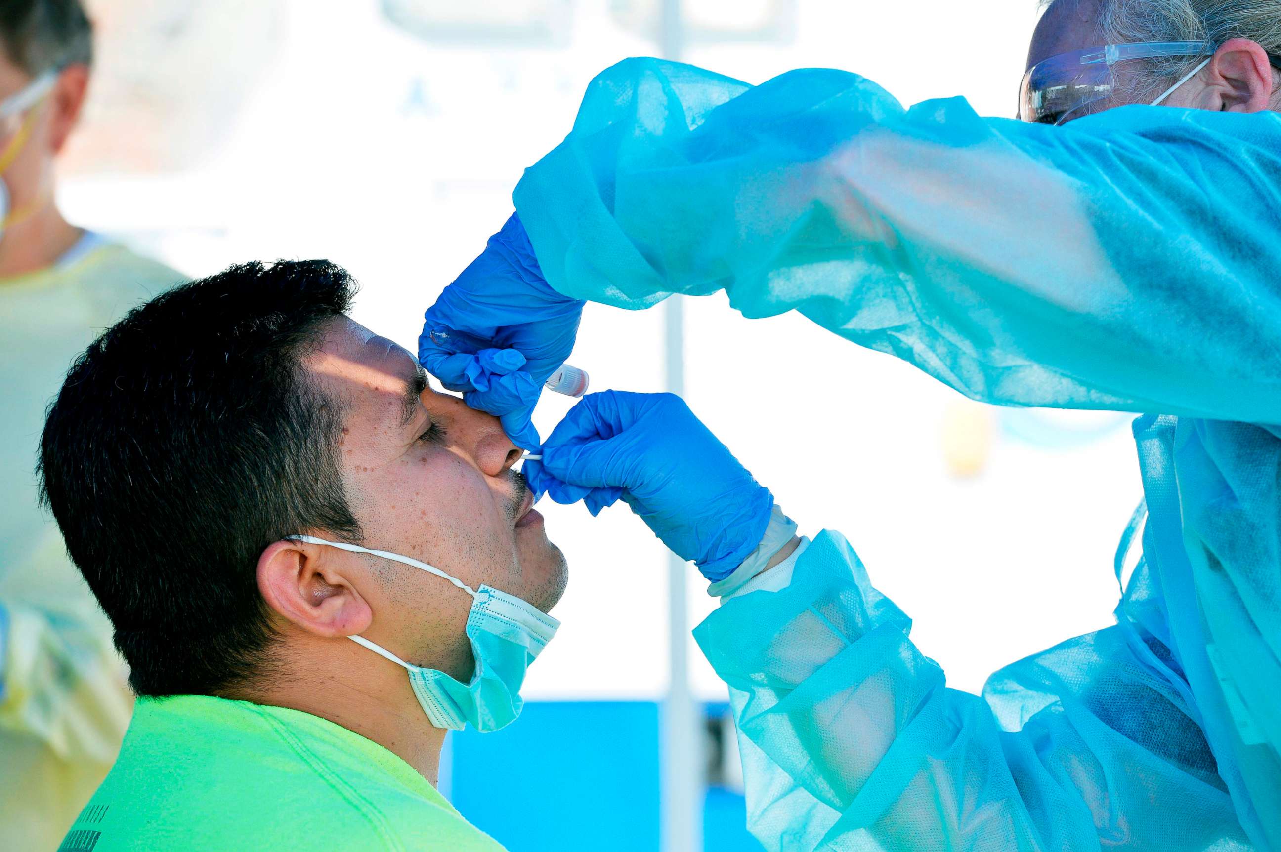 PHOTO: A health worker test a man for COVID-19 at a pop up testing location on the boardwalk at Revere Beach in Revere, Mass., on Aug. 11, 2020.