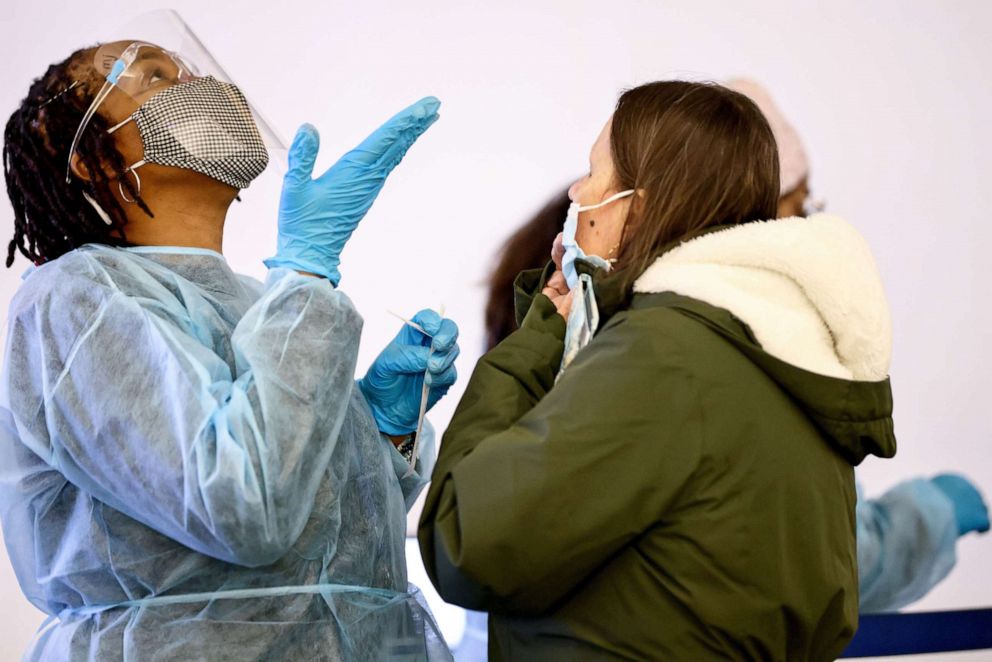 PHOTO: Merline Jimenez, left, provides direction before administering a COVID-19 nasopharyngeal swab to a person at a testing site at Los Angeles International Airport (LAX), Dec. 21, 2021 in Los Angeles.