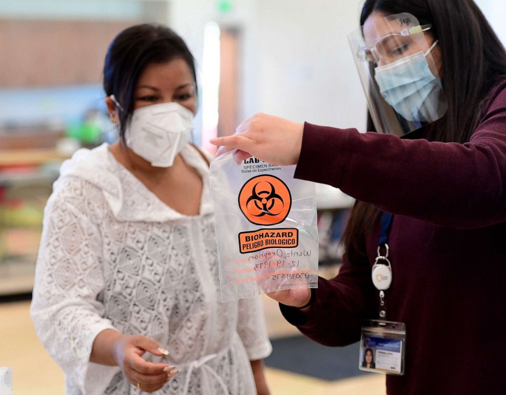 PHOTO: Walk in COVID-19 testing patient Oraphan Wentz (left) receives instructions from San Bernardino County general service worker Yesenia Lopez (right) prior to be tested at the Jessie Turner Health and Fitness in Fontana, Calif., March 22, 2022.
