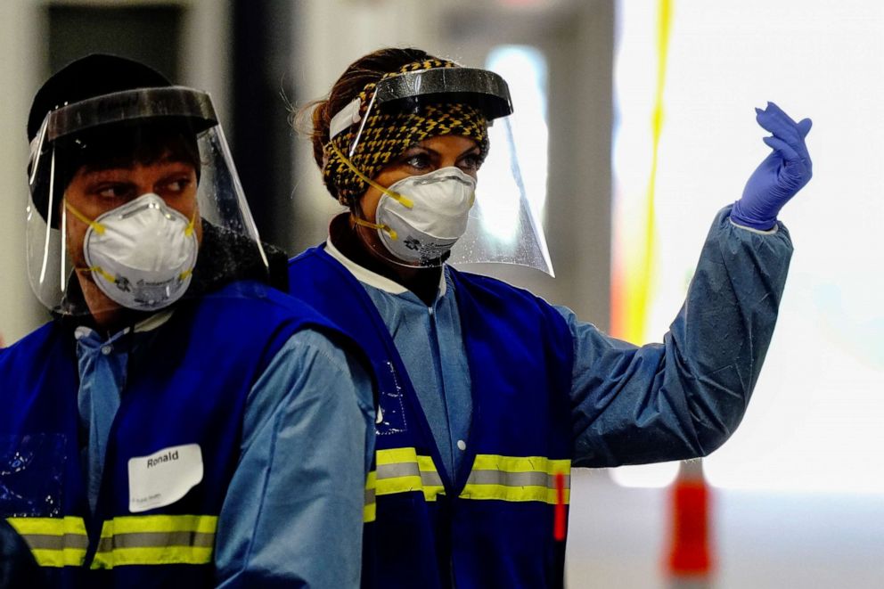 PHOTO: A health care worker beckons incoming cars at a drive-thru COVID-19 testing site inside the Alliant Energy Center complex, as the outbreak continues in Madison, Wis., Oct. 31, 2020.