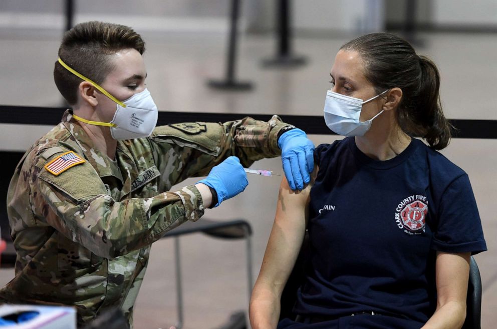 PHOTO: Spc. Katherine Deskins of the Nevada Army National Guard administers a Moderna COVID-19 vaccination to Clark County Fire Department Capt. Jasmine Ghazinour on the first day of Clark County's pilot vaccination program on Jan. 14, 2021, in Las Vegas.