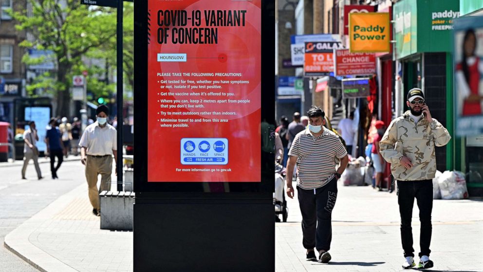 PHOTO: Pedestrians walk past a sign warning members of the public about the spread of COVID-19 in London on June 1, 2021.