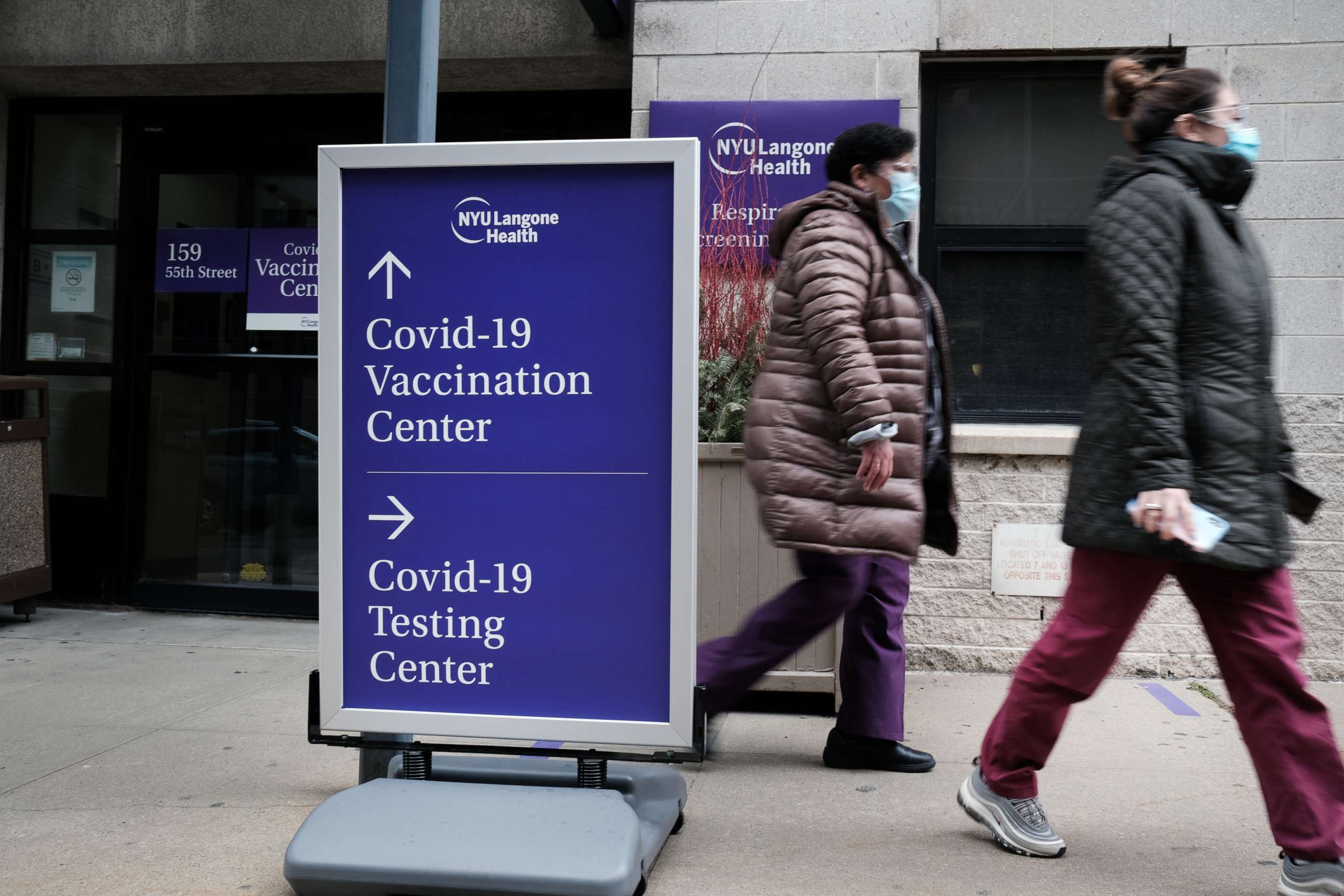 PHOTO: NEW YORK, NEW YORK - JANUARY 27: People walk by a sign for both a Covid-19 testing clinic and a Covid vaccination location outside of a Brooklyn hospital on January 27, 2021 in New York City. 