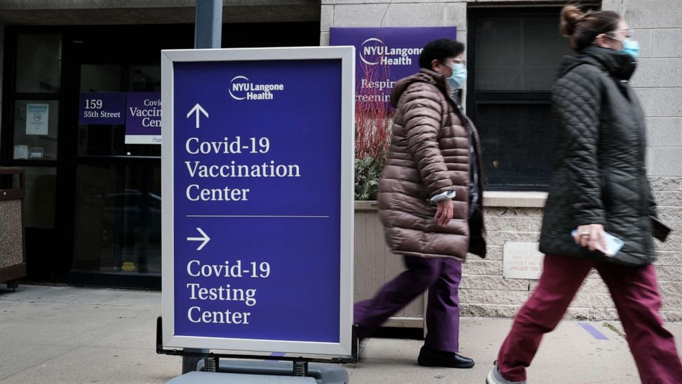 PHOTO: NEW YORK, NEW YORK - JANUARY 27: People walk by a sign for both a Covid-19 testing clinic and a Covid vaccination location outside of a Brooklyn hospital on January 27, 2021 in New York City. 