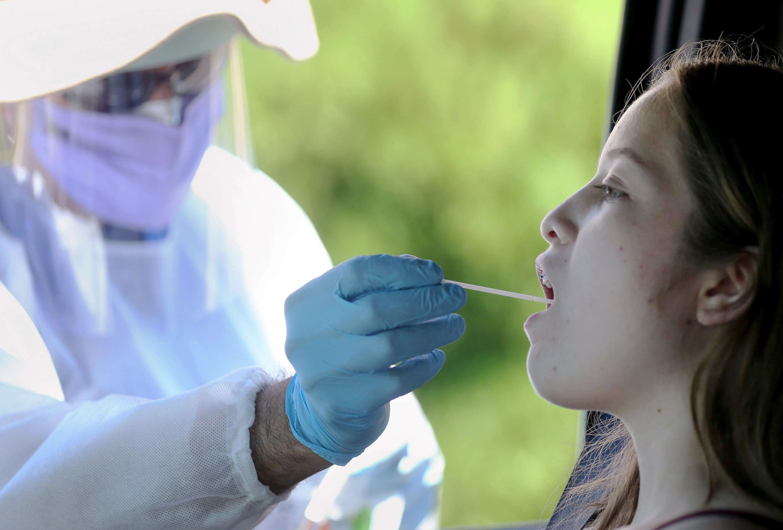 PHOTO: A healthcare worker gives a girl a throat swab test at a drive-in coronavirus testing center in Los Angeles, Aug. 11, 2020.