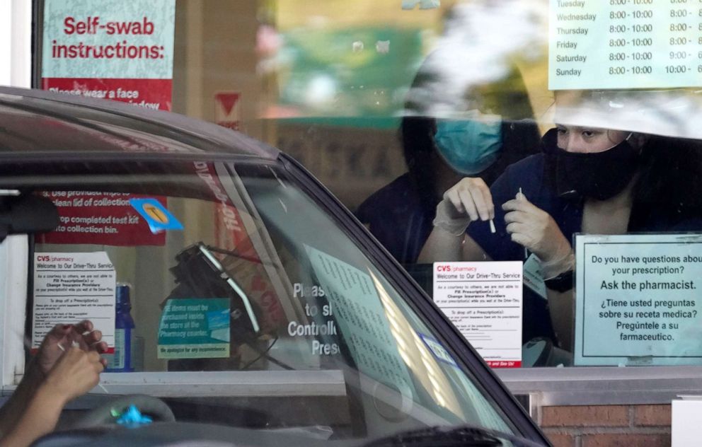 PHOTO: Pharmacy workers give instruction on how to administer a self COVID-19 nasal swab test at a drive-up CVS pharmacy in Dallas, Sept. 18, 2020. 