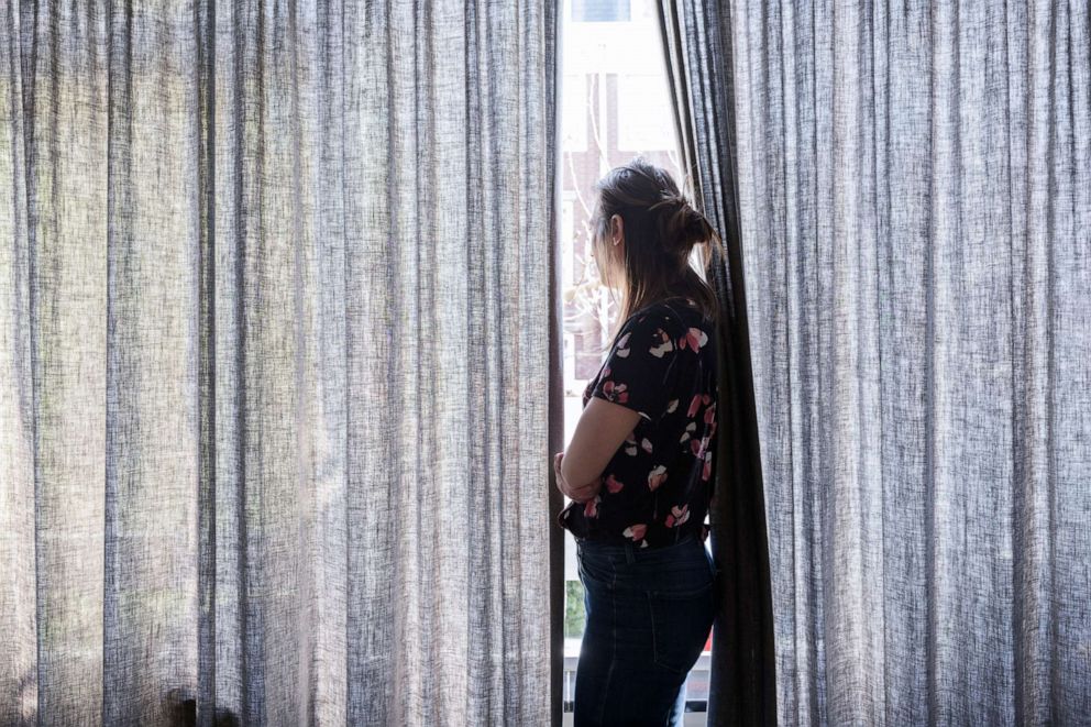 PHOTO: A woman looks out of a window in this stock photo.