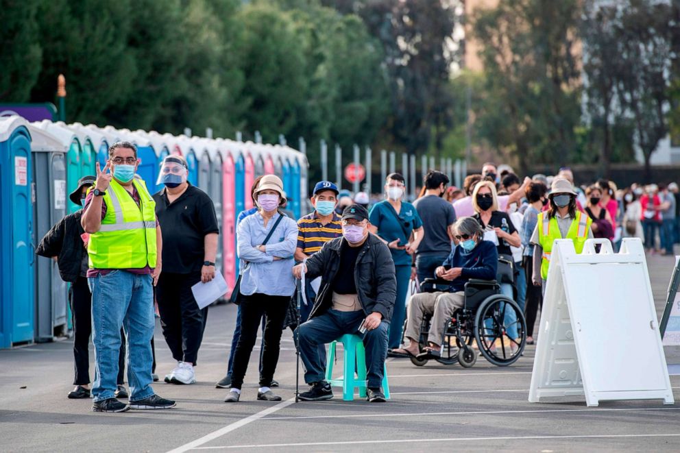 PHOTO: People wait in line in a Disneyland parking lot to receive Covid-19 vaccines on the opening day of the Disneyland Covid-19 vaccination "super Point-of-Dispensing" (POD) site, January 13, 2021, in Anaheim, California.