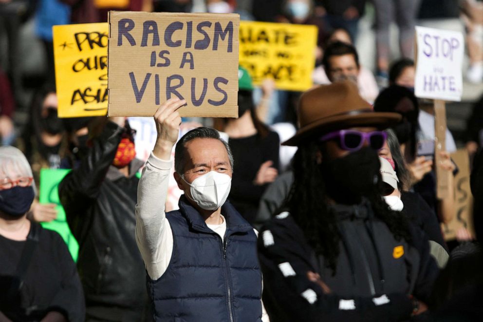 PHOTO: A man holds a sign that reads "Racism is a Virus" during the "We Are Not Silent" rally against anti-Asian hate in response to recent anti-Asian crime in the Chinatown-International District of Seattle, March 13, 2021. 