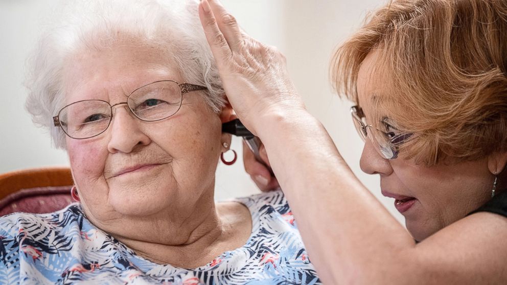 Janie York examines the ear of Elaine Martin at the SilverRidge Assisted Living facility in Gretna, Neb., in August 2018.