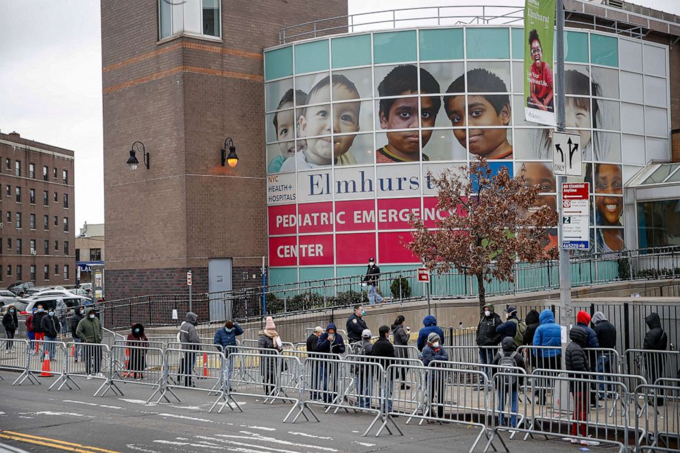 PHOTO: Patients wear personal protective equipment while maintaining social distancing as they wait in line for a COVID-19 test at Elmhurst Hospital Center, March 25, 2020, in New York.