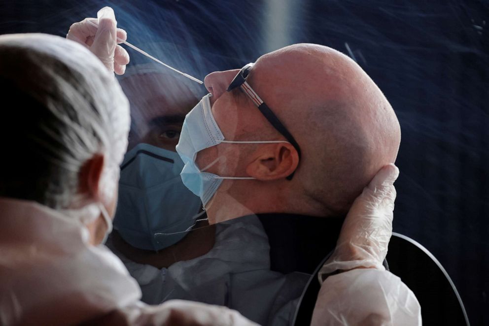 PHOTO: A health worker, wearing a protective suit and a face mask, administers a nasal swab to a patient in a temporary testing site for the coronavirus disease (COVID-19) in Lille, France, Oct. 26, 2020.