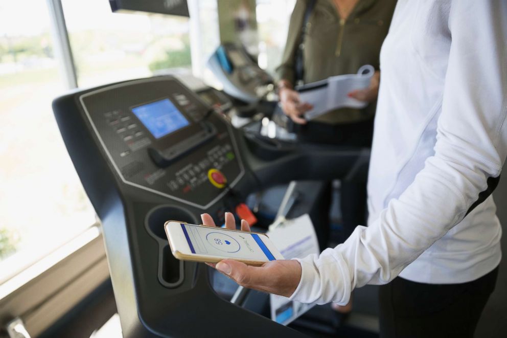 PHOTO: Woman with a smart phone fitness tracker on treadmill.