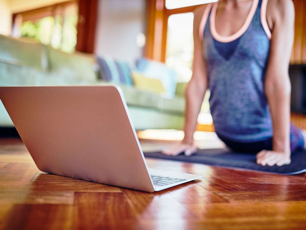 PHOTO: A woman performs yoga at home in front of a laptop computer in an undated stock photo.
