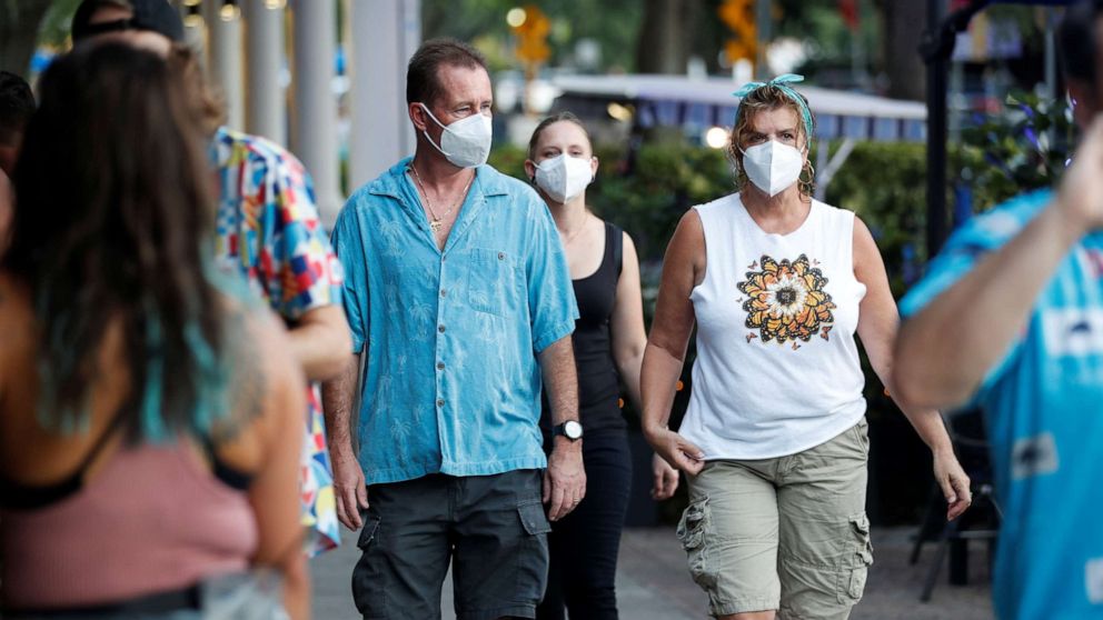 PHOTO: People wearing protective face masks walk in downtown St. Petersburg, Fla., Aug. 6, 2021.