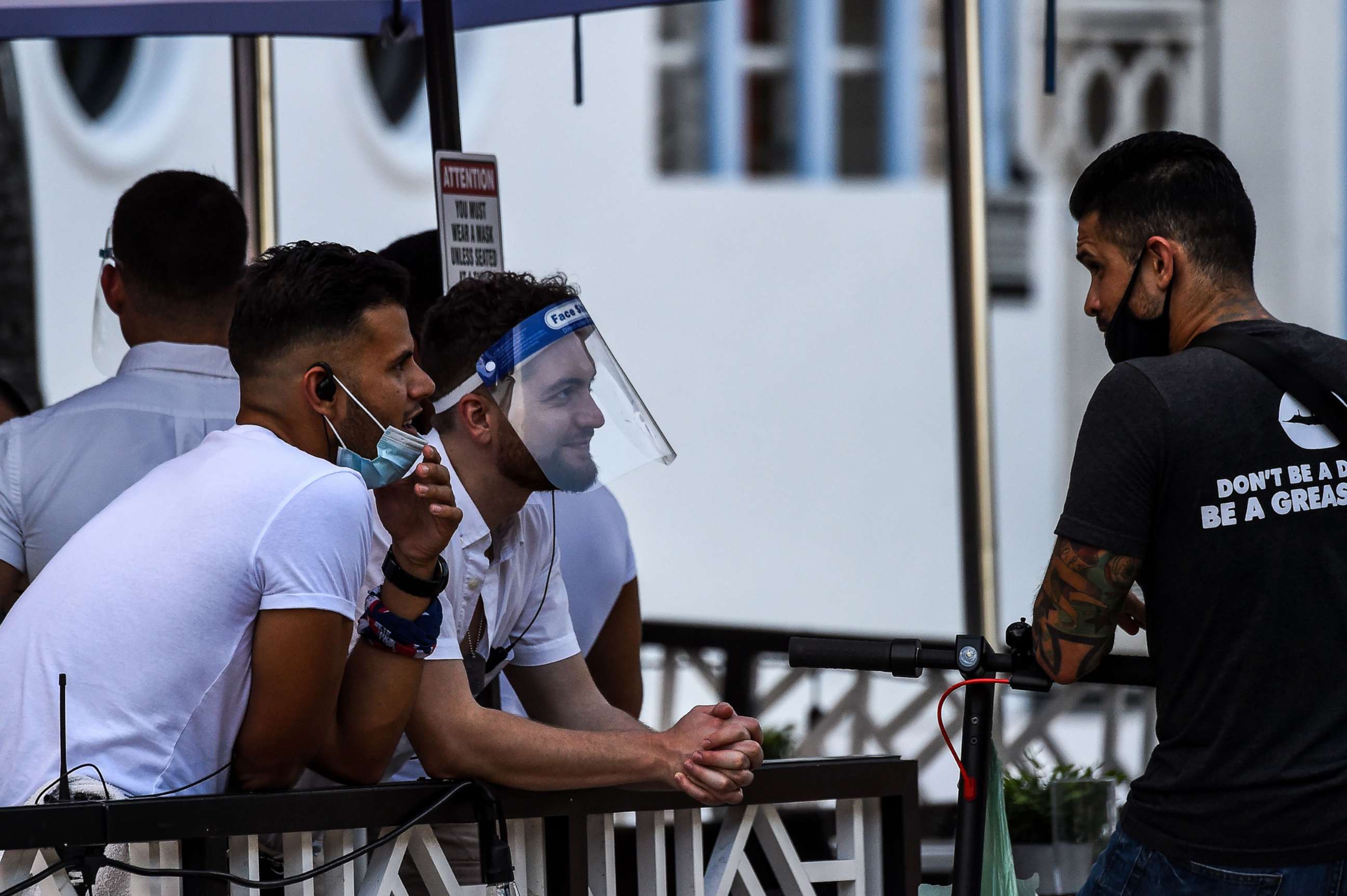 PHOTO: A waiter covers his face with a shield as he chat with another man at a restaurant on Ocean Drive in Miami Beach, Fla., on July 14, 2020, amid the coronavirus pandemic.