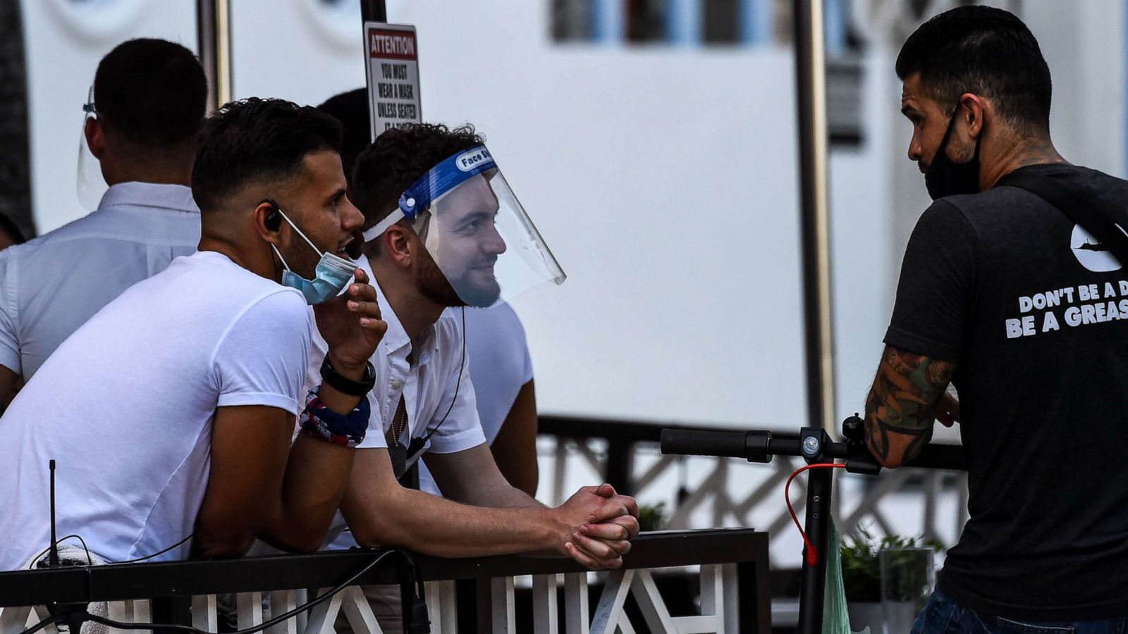 PHOTO: A waiter covers his face with a shield as he chat with another man at a restaurant on Ocean Drive in Miami Beach, Fla., on July 14, 2020, amid the coronavirus pandemic.