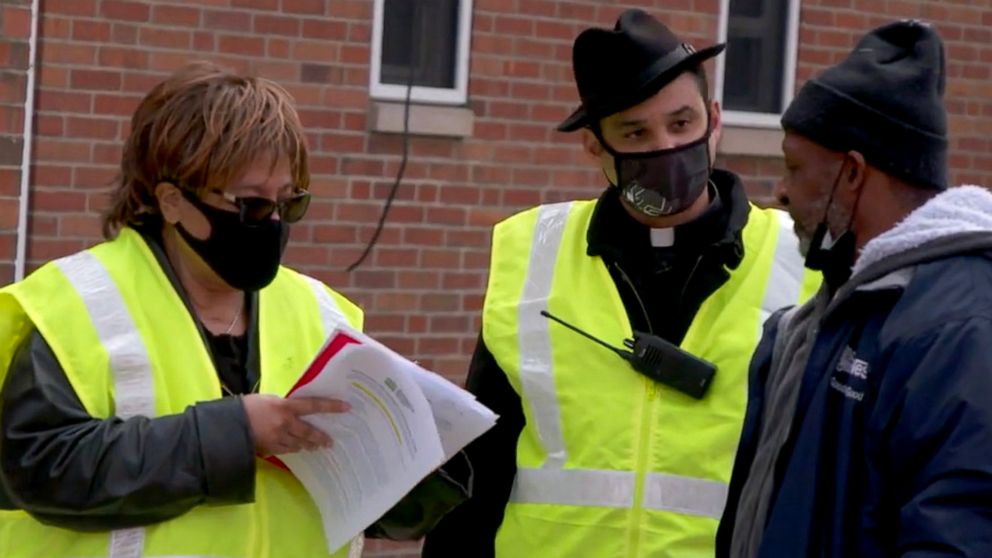 PHOTO: Father Paul Abernathy speaks with a resident of Pittsburgh, Pennsylvania's Hill District about taking a COVID-19 vaccine, as part of the Neighborhood Resilience Project. 