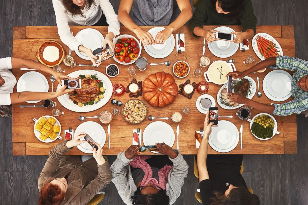 PHOTO: A stock photo depicts people using their phones during a holiday meal.