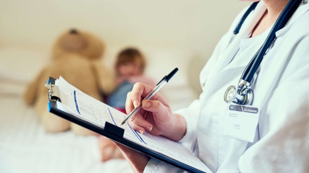 PHOTO: A doctor is pictured filling out a form while treating a child patient in this undated stock photo.