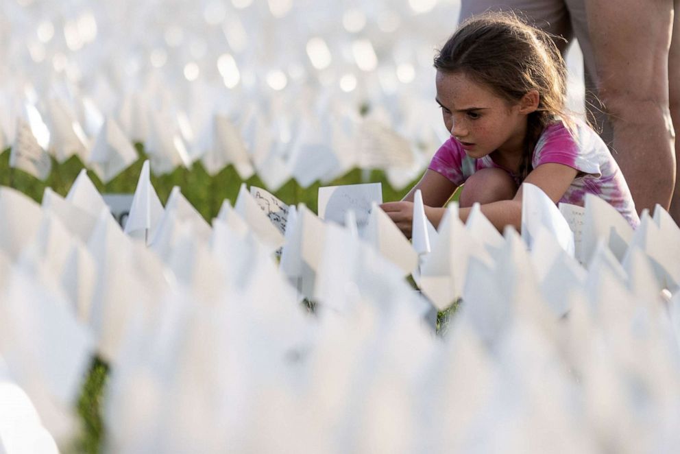 PHOTO: A child places a white flag on the National Mall in Washington, D.C., Sept. 18, 2021,  to honor lives lost to COVID-19 in the United States.