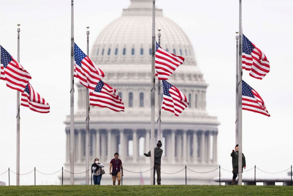 PHOTO: National Park employees lower American flags to half-staff to mark one million deaths from COVID-19 on the National Mall in Washington, D.C., May 12, 2022.