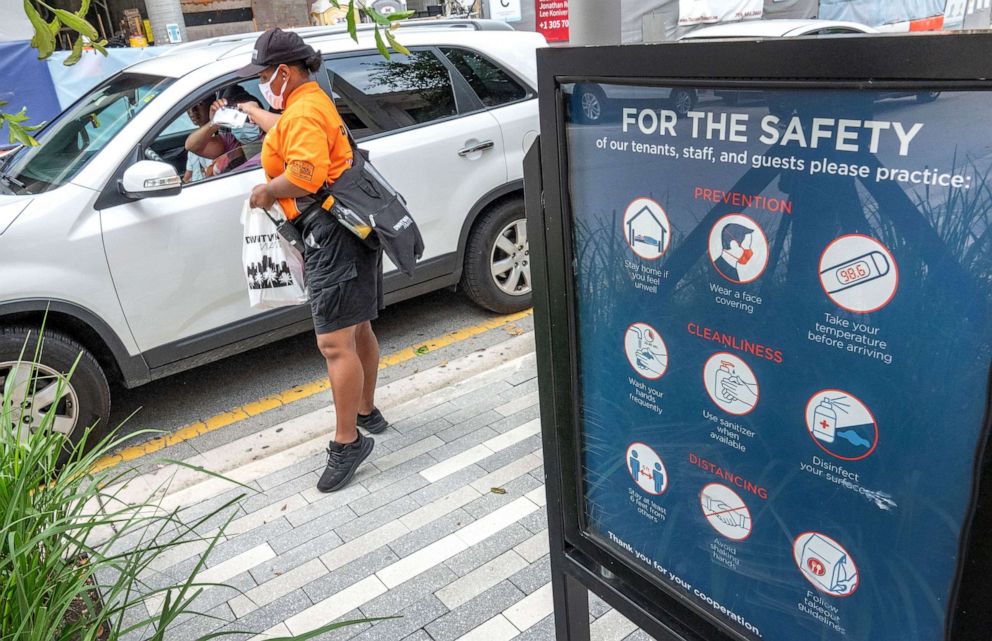 PHOTO: A woman distributes free face masks in downtown Miami, July 7, 2020.