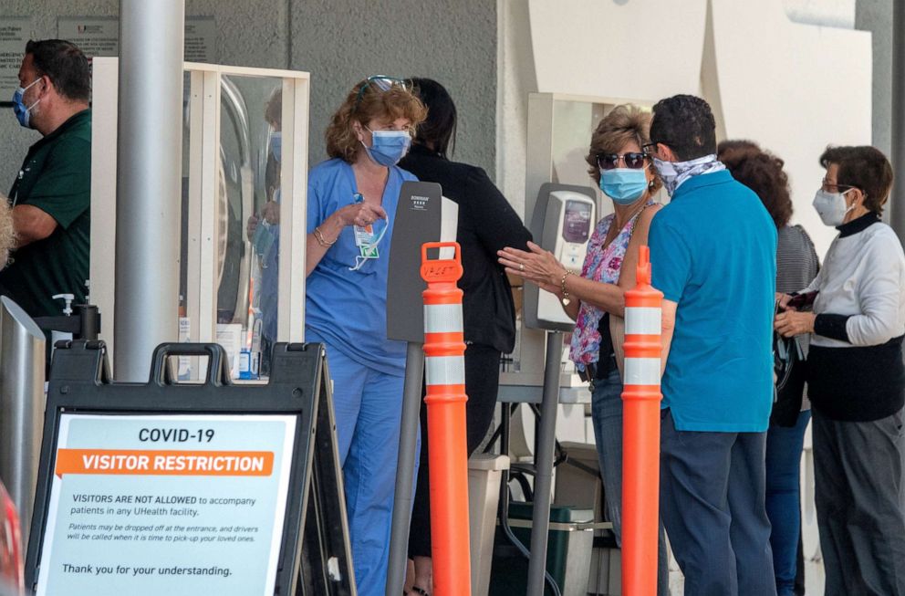 PHOTO: People wearing masks wait to enter to the Jackson Memorial Hospital in Miami, June 22, 2020.