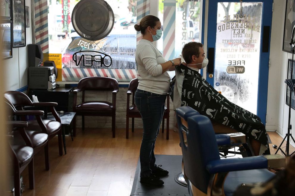 PHOTO: Angie O'Neill works on the hair of Phil Quinn as the Las Olas Barber shop opens on May 18, 2020 in Fort Lauderdale, Florida.