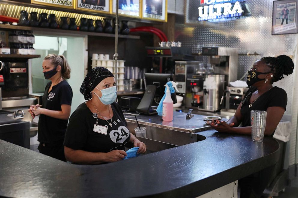 PHOTO: Linda Silvetti and Ericka Griffin (R) wait for customers as the Floridian restaurant opens on May 12, 2020 in Fort Lauderdale, Florida. 