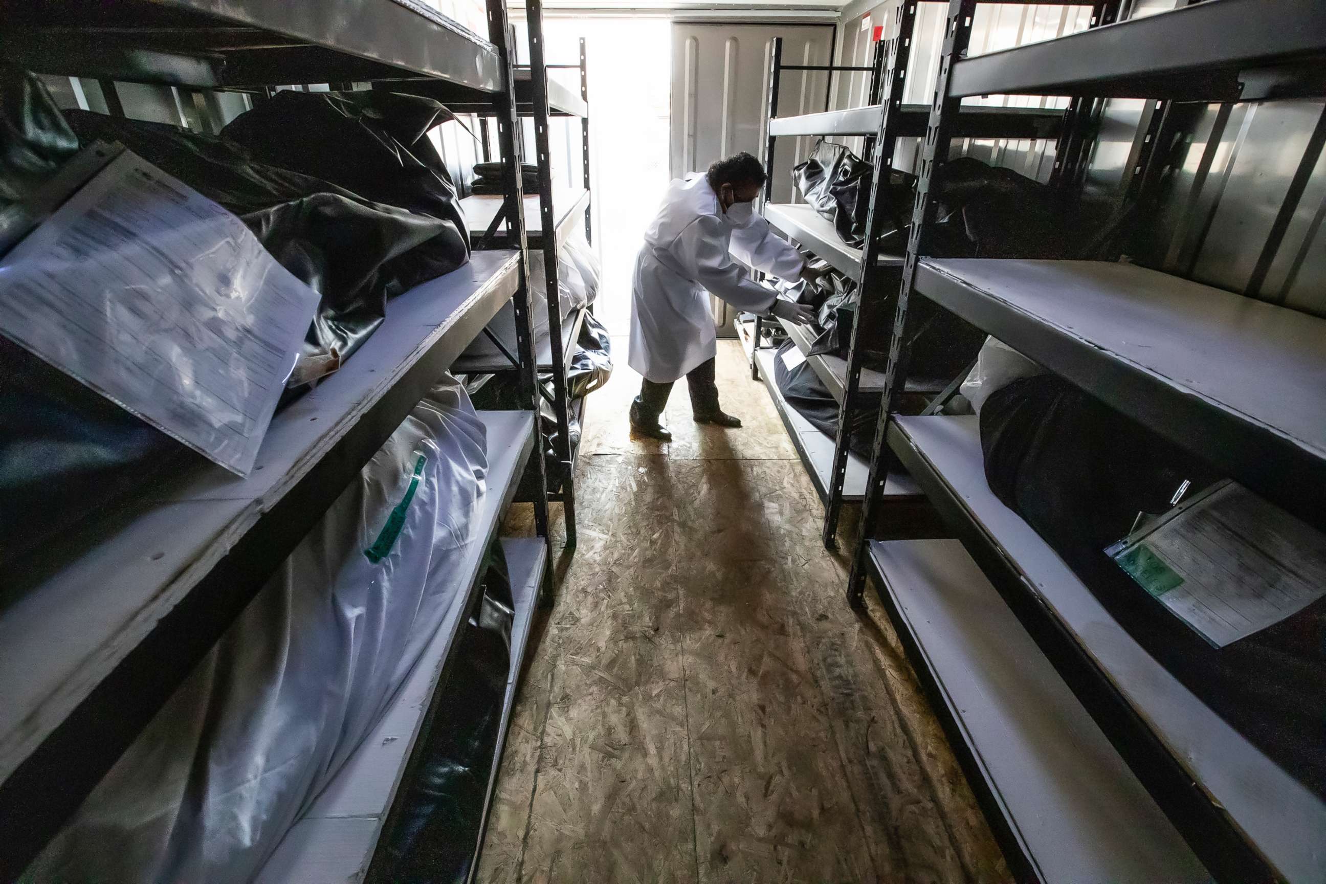 PHOTO: A funeral home driver handles one of the Covid-19 victims held stored in a mobile refrigerator outside the facility in Los Angeles, Aug. 21, 2020.